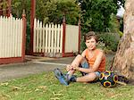 Portrait of boy with soccer ball sitting on grass tying trainer laces