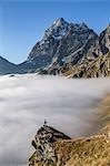 A solitary hiker admiring the profile of the Monviso (Monte Viso) emerging from the fog, Piedmont, Italy, Europe