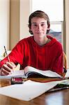 Portrait of teenage boy doing homework at dining room table