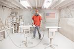 Portrait of cabinet maker with spray gun in workshop spray booth