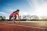 Young female athlete on her marks at race start line