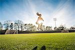 Young female athlete doing jump training on sports field