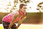 Young tattooed female athlete taking a break on sports field