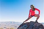 Young female trail runner stretching on rock on Pacific Crest Trail, Pine Valley, California, USA