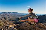 Rear view of young female trail runner crouching and touching toes,Pacific Crest Trail, Pine Valley, California, USA