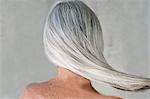 Rear view of bare shouldered mature woman with long grey hair