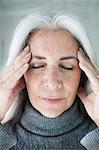 Close up of mature woman meditating with eyes closed and hands on forehead