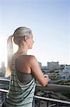 Mature woman in sports clothing leaning against city balcony