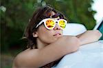 Woman wearing sunglasses reflecting palm trees