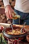 Man preparing fish dish, adding olive oil