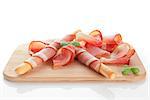 Prosciutto slices with breadstick and fresh basil on wooden cutting board isolated on white background. Culinary italian ham.