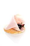 Delicious canape with ham, black olive and fresh rosemary herb isolated on white background. Culinary eating.