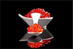 Caviar in spoon and in bowl isolated on black background. Luxury culinary food background.