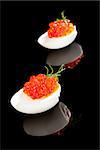 Delicious red caviar in egg isolated on black background. Luxury culinary food.