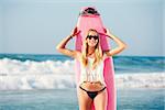 A beautiful surfer girl at the beach with her surfboard