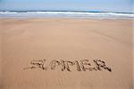 summer word written on brown sand ground low tide beach ocean seashore in Spain Europe