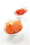 Smoked salmon and red caviar in white bowls isolated on white background. Culinary seafood concept.