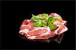 Proscuitto slices isolated on black background with lamb's lettuce. Culinary ham still life.