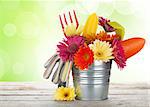 Colorful flowers and garden tools on wooden table with sunny bokeh