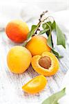 Branch with ripe apricots on white wooden table.