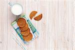 Cup of milk and gingerbread cookies on white wooden table with copy space