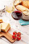 White and red wine, cheese and bread on white wooden table