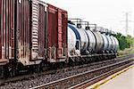 End of line of freight train tanker cars in perspective parallel to tracks.