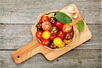 Colorful cherry tomatoes on cutting board over wooden table background