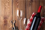 Red wine bottle, glasses and corkscrew on wooden table background. Top view with copy space
