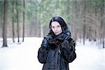 Brunette girl wearing a fur coat in winter forest