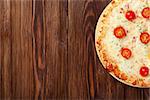 Italian pizza with cheese, tomatoes and basil on wooden table. Top view with copy space