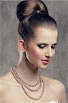 close-up portrait of fine brunette woman with elegant hair-style, stylish make-up and precious pearl necklace