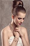 lovely elegant female posing in close-up fashion shoot with fine hairstyle, cute white dress and precious pearls jewellery