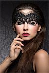 Beautiful, stunning, romantic woman with long brown hair, beautiful, dark make up with little pattern, transparent, black mask on her face. She is looking at camera.