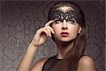 Beautiful, gorgeous, stunning brunette woman with long hair. Wearing transparent, black mask dark make up with little pattern and pink lips.