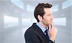 Thinking businessman touching his chin against bright white room with windows