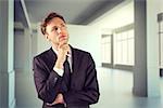 Young businessman thinking with hand on chin against white room with screen