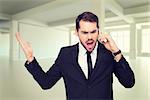 Angry businessman gesturing on the phone against white room with windows