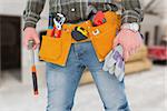 Manual worker holding gloves and hammer against workshop