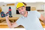 Smiling repairman holding power drill against workshop