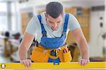 Worker using spirit level against workshop