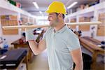 Worker with plank of wood against workshop