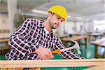 Handyman using hammer on wood  against workshop