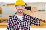 Handyman holding wood planks against workshop