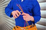 Electrician cutting wire with pliers against grey shutters