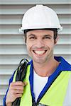 Happy electrician with wire against white background against grey shutters