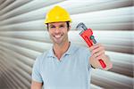 Happy carpenter holding monkey wrench against grey shutters