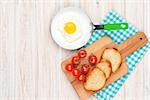 Healthy breakfast with fried egg, tomatoes and toasts on white wooden table. Top view with copy space