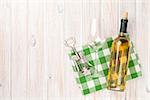 White wine bottle, glass and corkscrew on white wooden table background. Top view with copy space