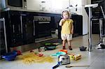 A 2 years old little girl posing in a kitchen in which she made the mess